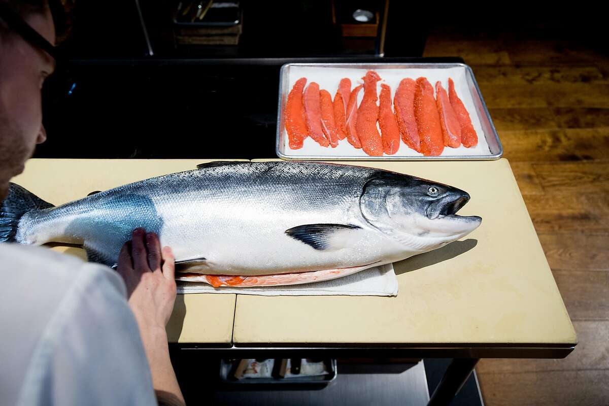 Lazy Bear sous chef Matt Hanley examines a king salmon on Wednesday, Aug. 2, 2017, in San Francisco.