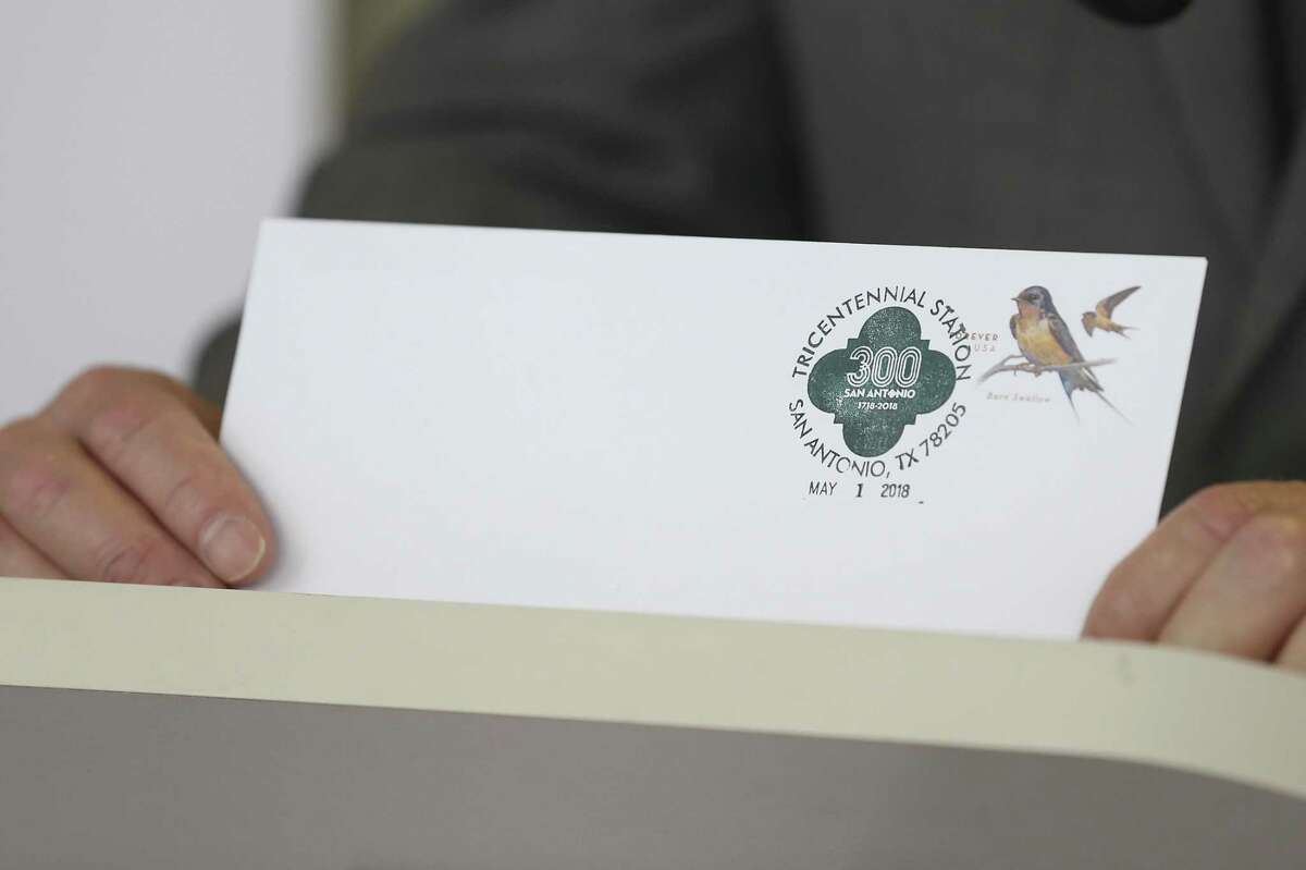 San Antonio Postmaster Robert D. Carr, Jr., holds up an envelope with the San Antonio Tricentennial Cancellation Postmark during a press conference at the Arsenal Post Office, Monday, April 30, 2018. The postmark will only be available through the month of May at the Arsenal Post Office.
