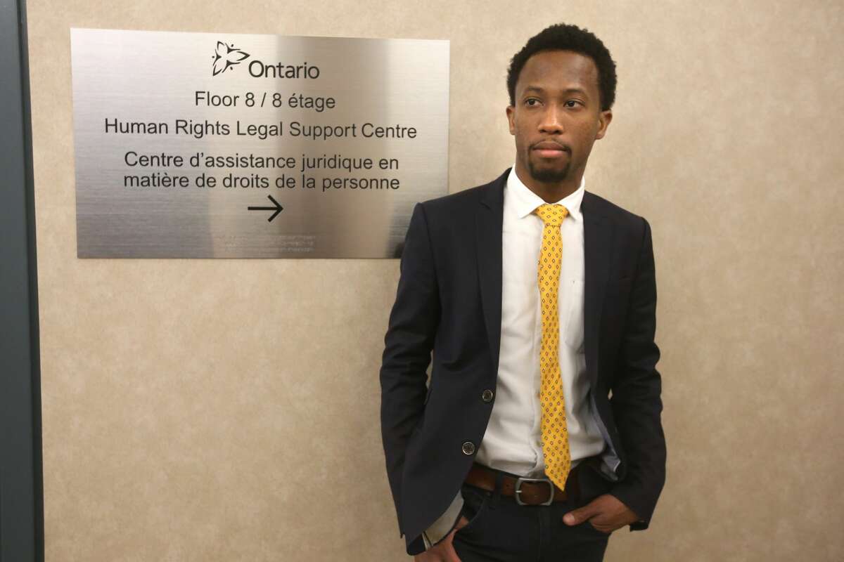 Emile Wickham, who just won a discrimination case with the Ontario Human Rights Tribunal against a restaurant, Hong Shing Chinese restaurant, for violating his human rights in asking him and his friends (all Black) to prepay for their meal poses for pictures in front Ontario Human Rights Tribunal office's.