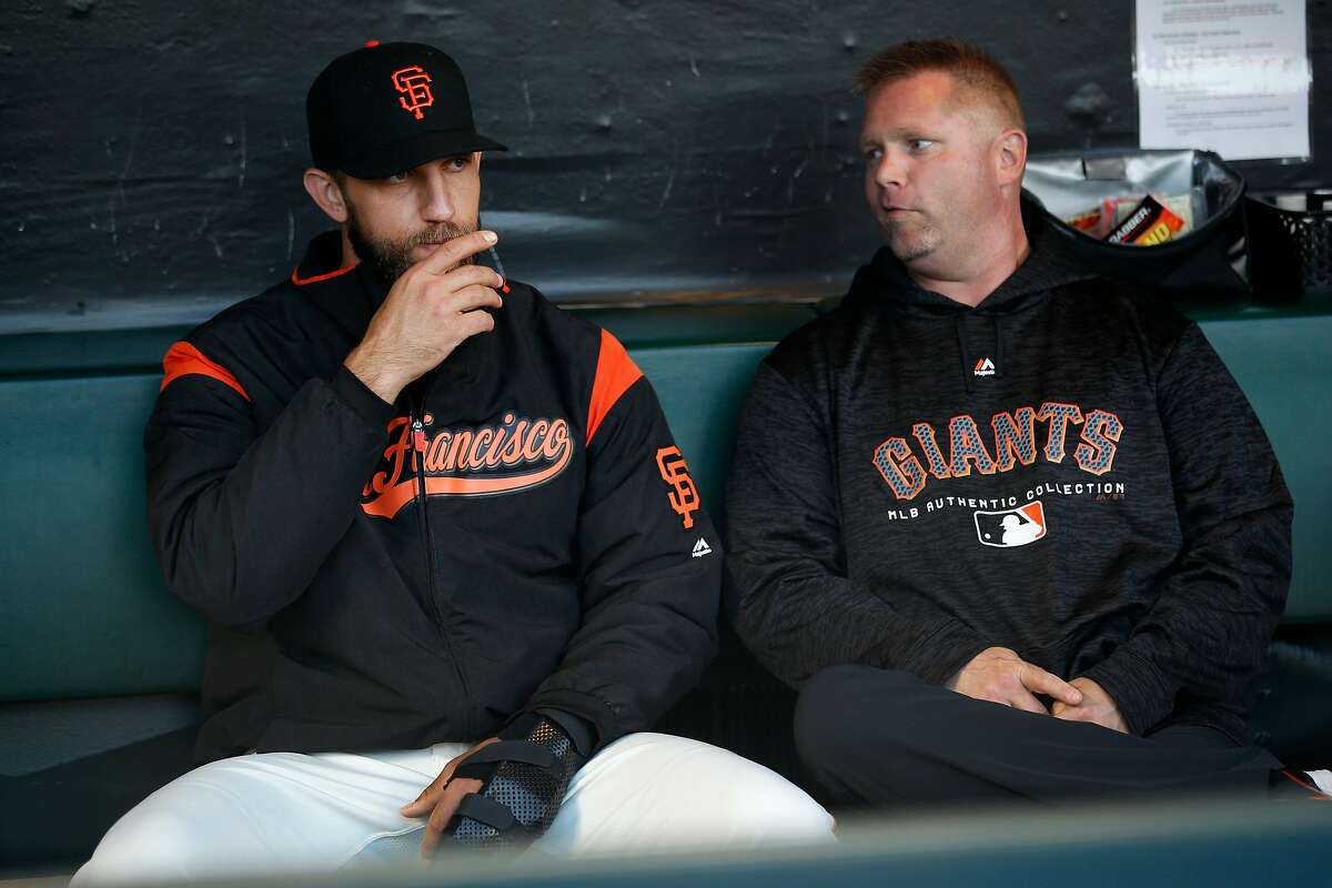 From left: San Francisco Giants starting pitcher Madison Bumgarner (40), wearing a wrist guard, and Carl Kochan, who is the Giants strength and conditioning coach, chat before an MLB game between the San Francisco Giants and Arizona Diamondbacks at AT&T Park, Tuesday, April 10, 2018, in San Francisco, Calif.