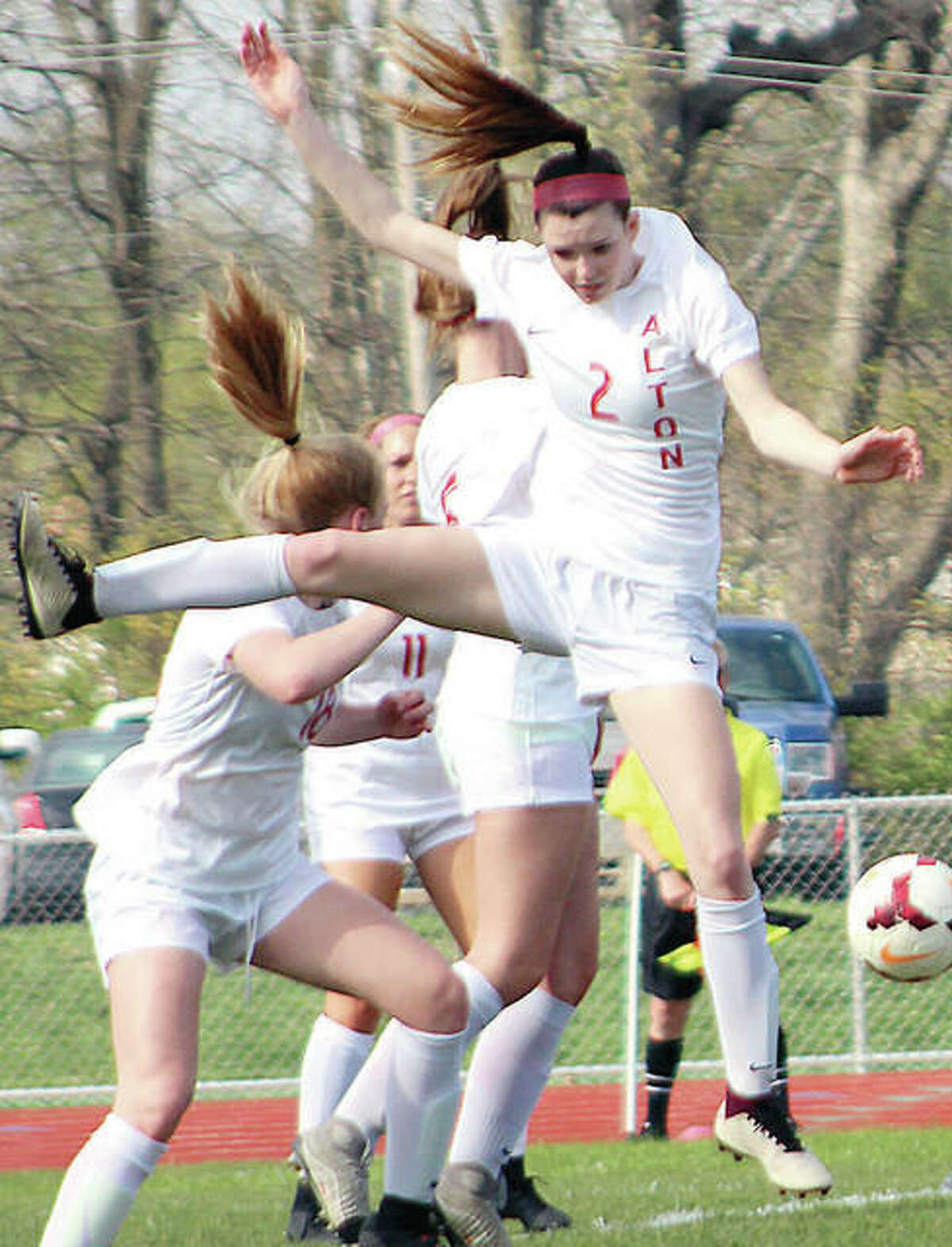 Megan Zini of Alton (2) goes high to deflect the ball during action against Edwardsville Thursday at Alton High.