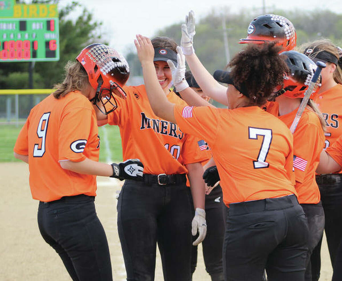Gillespie’s Mackenzie Kasarda (left) is greeted by teammates at home plate after hitting a home run to cap the scoring in the Miners’ SCC win in Piasa.