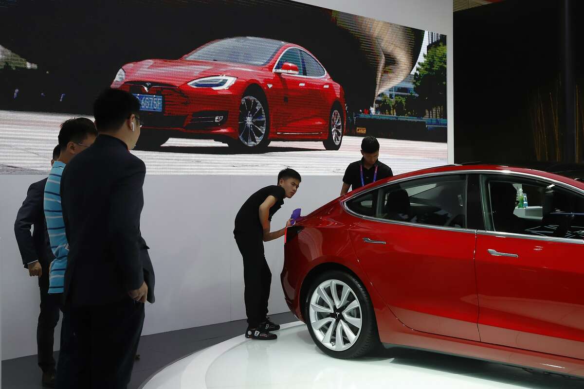 A worker cleans a sedan from Tesla during Auto China 2018 in Beijing, China, Thursday, April 26, 2018. Auto China 2018, the industry's biggest sales event this year, is overshadowed by mounting trade tensions between Beijing and U.S. President Donald Trump, who has threatened to hike tariffs on Chinese goods including automobiles in a dispute over technology policy. (AP Photo/Ng Han Guan)