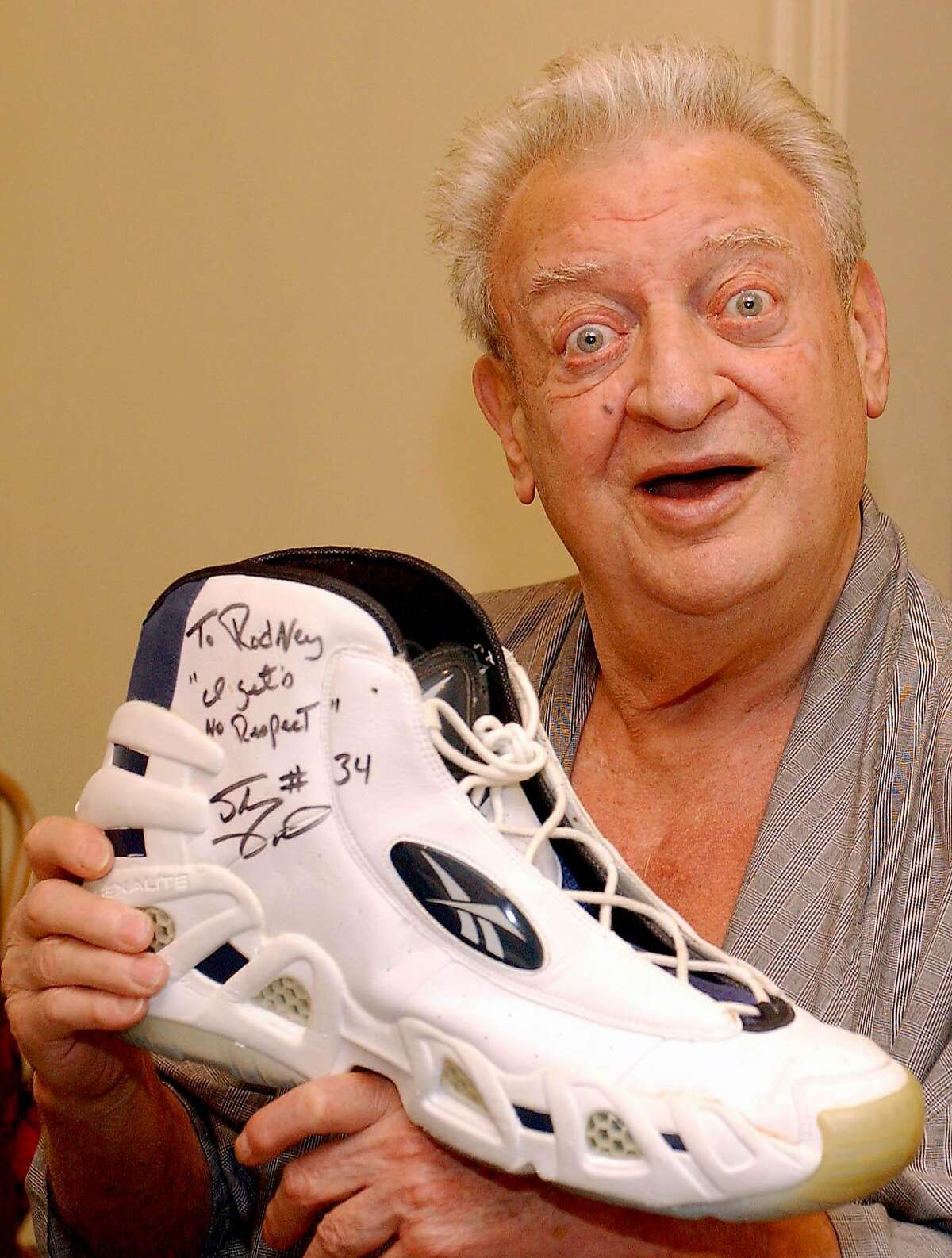 ** FILE ** Comedian Rodney Dangerfield holds up a shoe autographed by Shaquille O'Neal that says "To Rodney, 'I gets No Respect' Shaq #34," at his home in Los Angeles during a photo session for the Orlando Sentinel football preview section, as shown in this July 28, 2004, file photo. On Tuesday, Oct. 5, 2004, Dangerfield died. He was 82. (AP Photo/Orlando Sentinel, John Raoux)