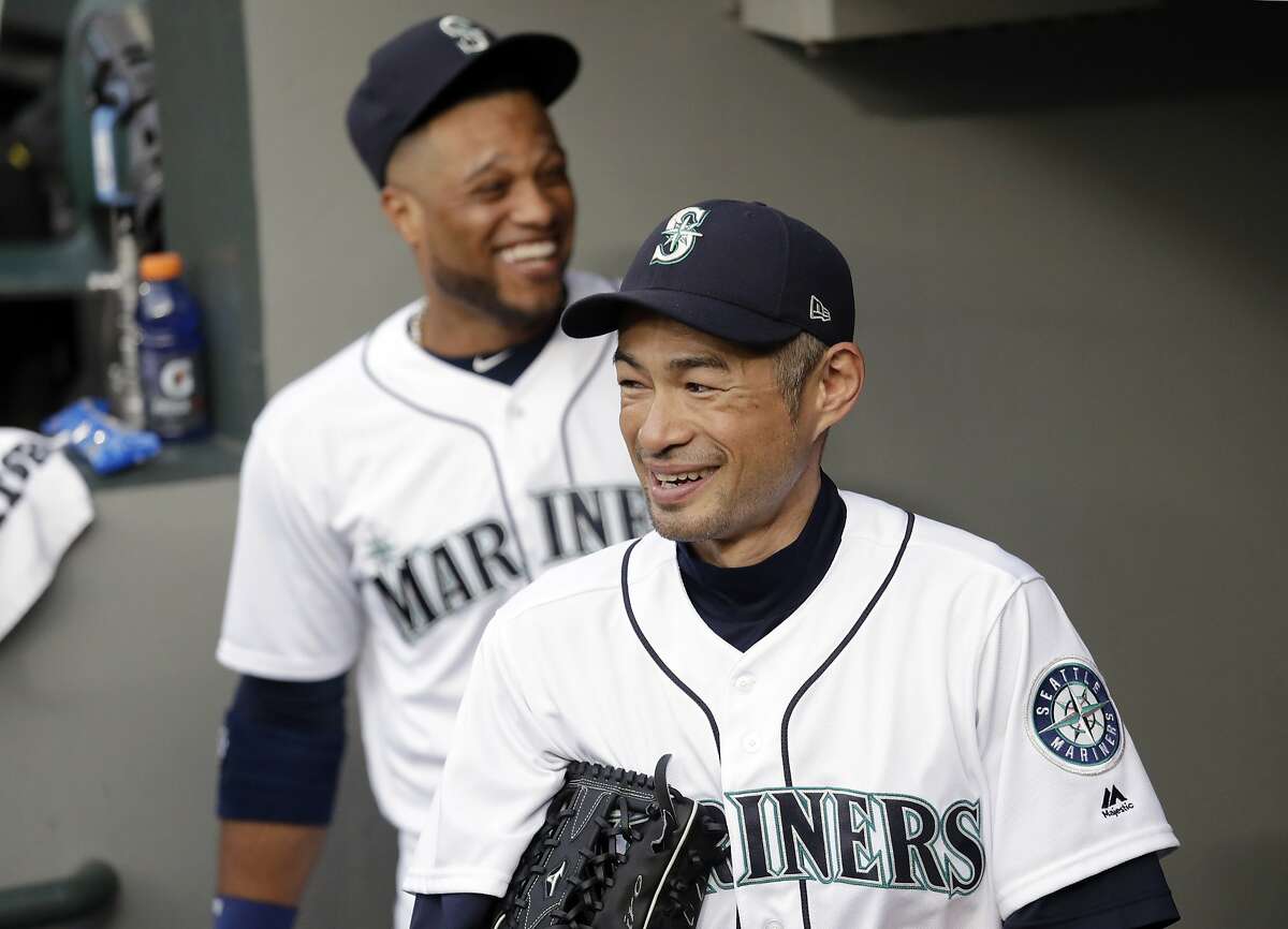 Seattle Mariners' Ichiro Suzuki, right, stands with Robinson Cano in the dugout before a baseball game against the Oakland Athletics Wednesday, May 2, 2018, in Seattle. (AP Photo/Elaine Thompson)