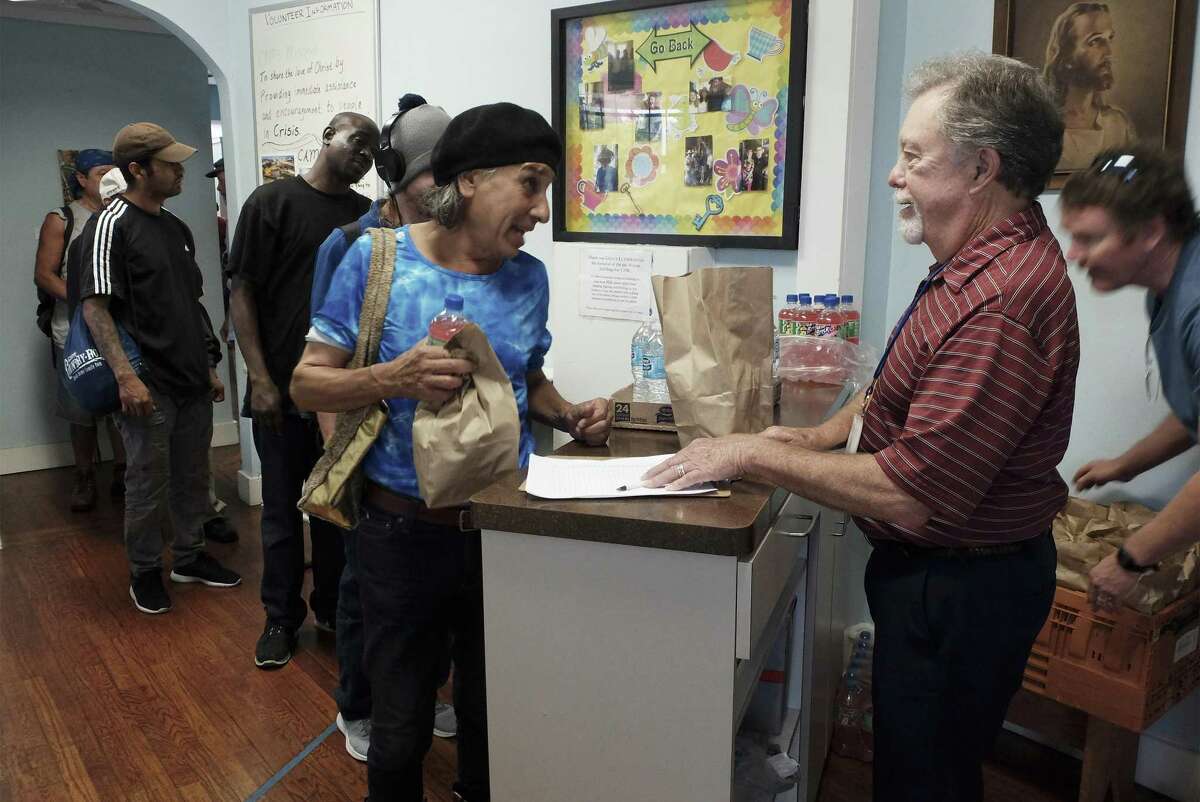 Volunteer Gates Whiteley, right, distributes sack lunches to the homeless at Christian Assistance Ministries in downtown San Antonio on May 3, 2018. The annual count of homeless people in Bexar County in January showed a steep rise in those living on the street. CAM serves 75 sack lunches to the needy each day.
