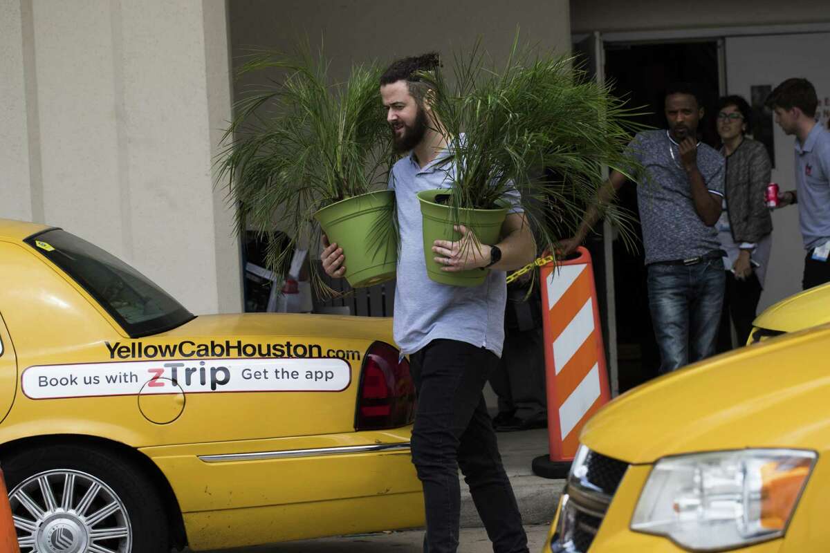 A man carries out decorative plants on the last day of the Offshore Technology Conference, Thursday, May 3, 2018, in Houston. ( Marie D. De Jesus / Houston Chronicle )
