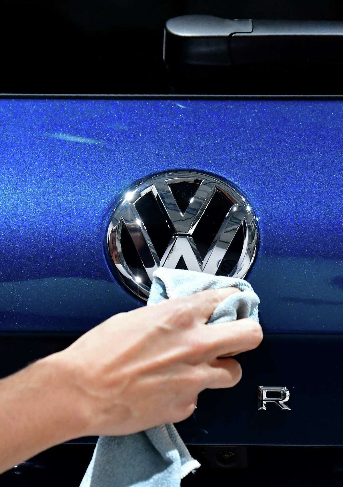 A staff member cleans a logo of an SUV VW Touareg on display ahead of the annual general meeting of German carmaker Volkswagen, in Berlin on May 3, 2018. / AFP PHOTO / Tobias SCHWARZTOBIAS SCHWARZ/AFP/Getty Images