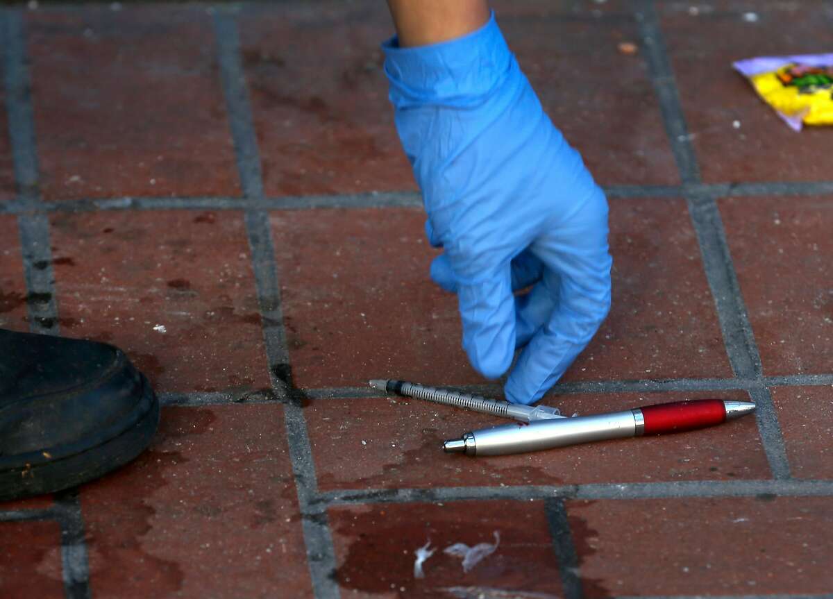 Michael Lopez, with the Central Market Community Benefit District, picks up a needle and other debris lying on the sidewalk on Market Street near Seventh Street in San Francisco, Calif. on Tuesday, March 6, 2018.