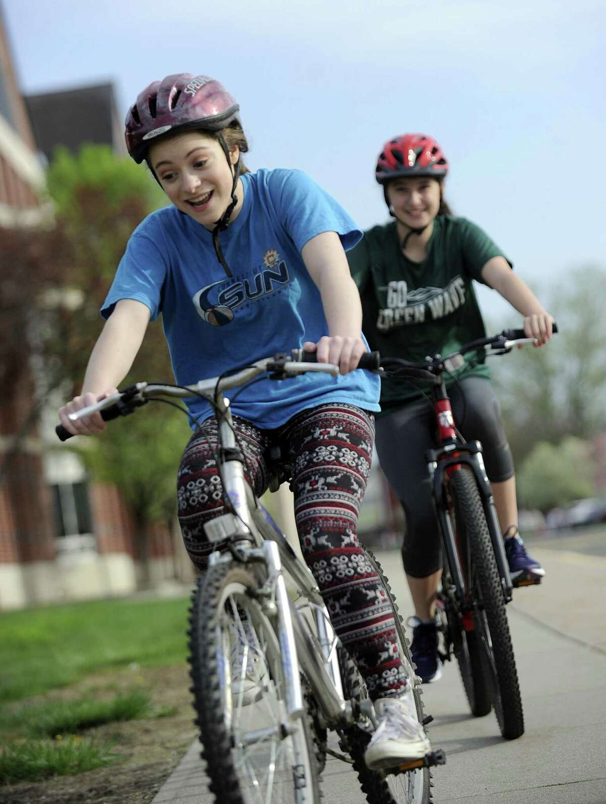 McKenna Riedl, 14, left, and Lilian Vito, 15, ride bicycles around New Milford High School Monday morning. The school started a new bike safety initiative where students learn these skills in gym class.