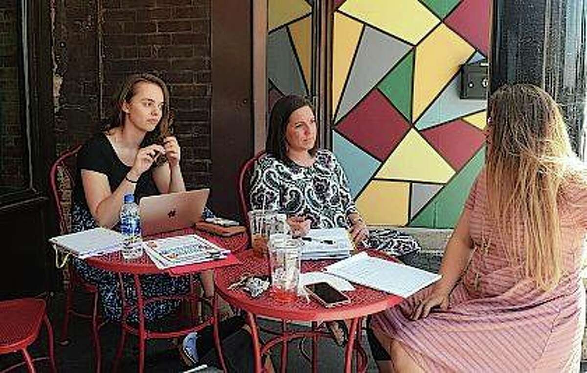 Abby Olmsted (from left) of Rochester, Ashley Earles of Mechanicsburg and Delaney Sieving of Jacksonville sit outside Soap Co. Coffee Shop on Tuesday as they plan this year’s Diapers to Backpacks event. The event is in August, but the social services group Community Connection Point is still looking for backpacks for it.