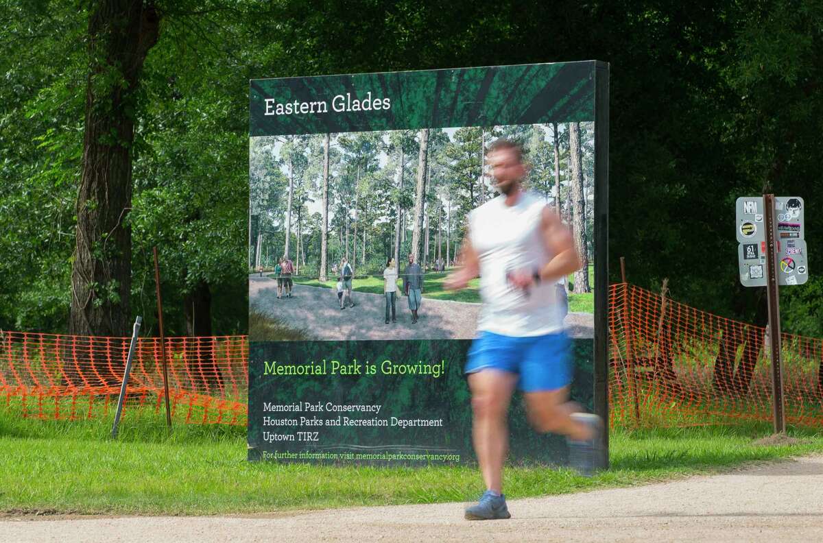 In this Wednesday, April 25, 2018 photo, a runner passes a sign referencing the construction currently underway on the Eastern Glades section of Memorial Park, in Houston. The Kinder Foundation, a charitable organization established by Richard Kinder, co-founder of energy company Kinder Morgan, and his wife Nancy are donating $70 million to the Memorial Park Conservancy. (Mark Mulligan/Houston Chronicle via AP)