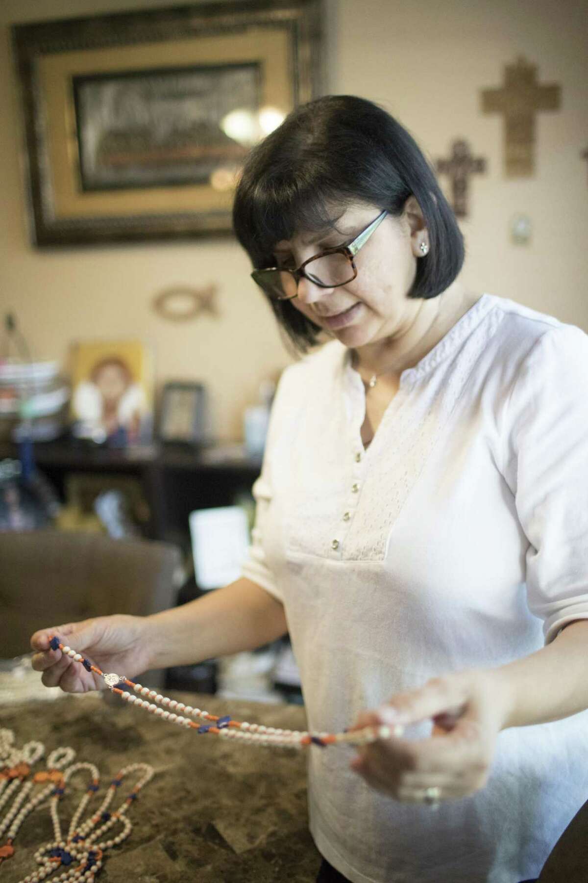 Maria Esther Aguilera takes a look at one of her Astros rosaries at her home, Monday, May 7, 2018, in Houston. Aguilera who makes rosaries has been working at least four hours a day making Astros rosaries to raise funds for the Annunciation Catholic Church. ( Marie D. De Jesus / Houston Chronicle )