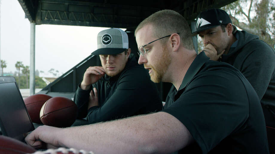 In this April 19, 2018, photo provided by Wilson Sporting Goods, quarterback Sam Darnold, left, and his mentor, former quarterback Jordan Palmer, right, look on as Wilson Labs engineer Dan Hare explains data gathered from throwing a football using the Wilson Connected Football System, at San Clemente High School in San Clemente, Calif. Darnold, the New York Jets rookie quarterback, was at his old stomping grounds in California last month tossing "smart" footballs equipped with computer chips with Palmer, that were calculating his every throw. (Wilson Sporting Goods via AP) / Wilson Sporting Goods