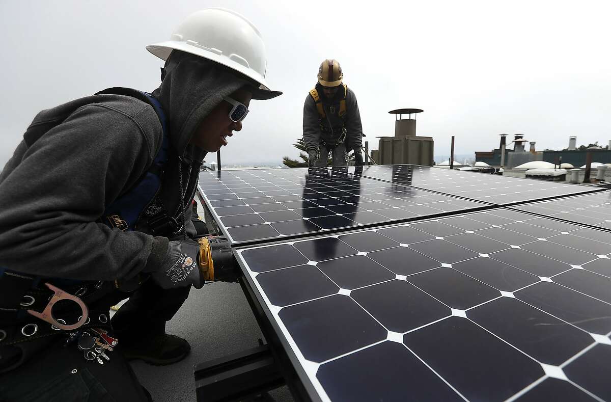 Luminalt solar installers Pam Quan (L) and Walter Morales (R) install solar panels on the roof of a home on May 9, 2018 in San Francisco.