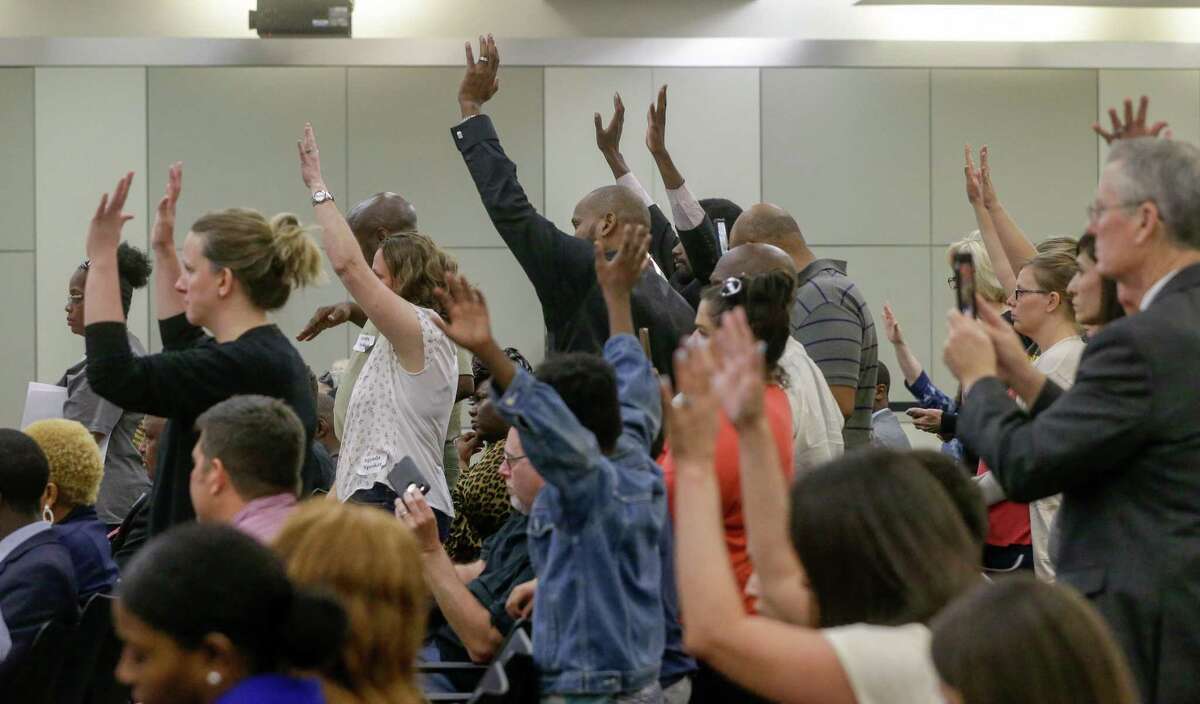 People wave their hands in response to a speaker during the Houston ISD board meeting Tuesday, April 24, 2018. The trustees were scheduled to vote on whether to hand over control of 10 chronically low-performing schools to Energized For STEM Academy, which already runs four in-district HISD charters. Many of the large crowd attending the meeting are against the partnership. ( Melissa Phillip / Houston Chronicle )