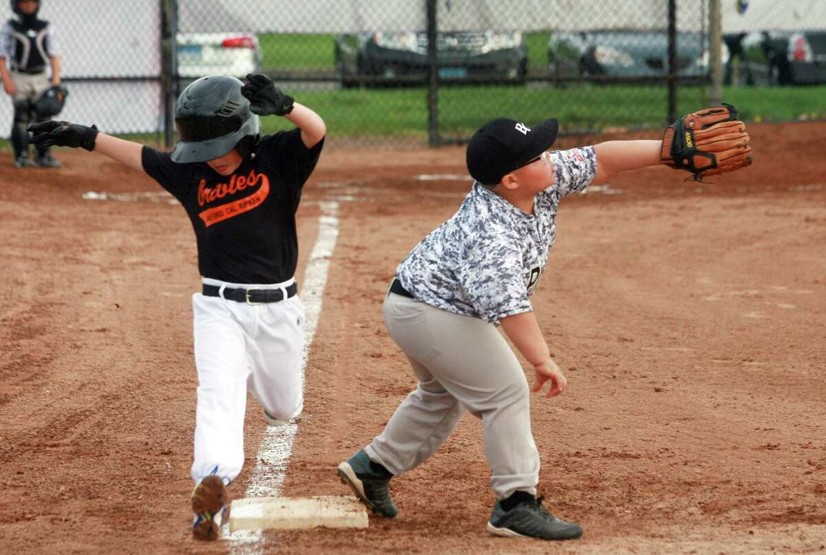 The Orioles' Owen Greggis, 5, hits first base as Ponce's Giovanni Barbosa tries to make the tag during Bridgeport Caribe League baseball at Seaside Park in Bridgeport, Conn., on Friday May 4, 2018. The organization is celebrating its 15th year. It has grown from strictly a baseball organization to where it now includes educational components.