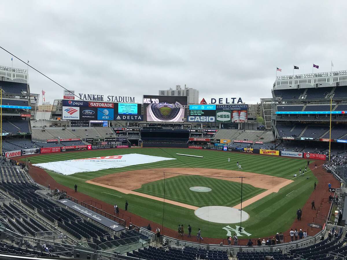 Dark skies threaten rain and the tarp is ready to be rolled out at Yankee Stadium on Sunday morning.