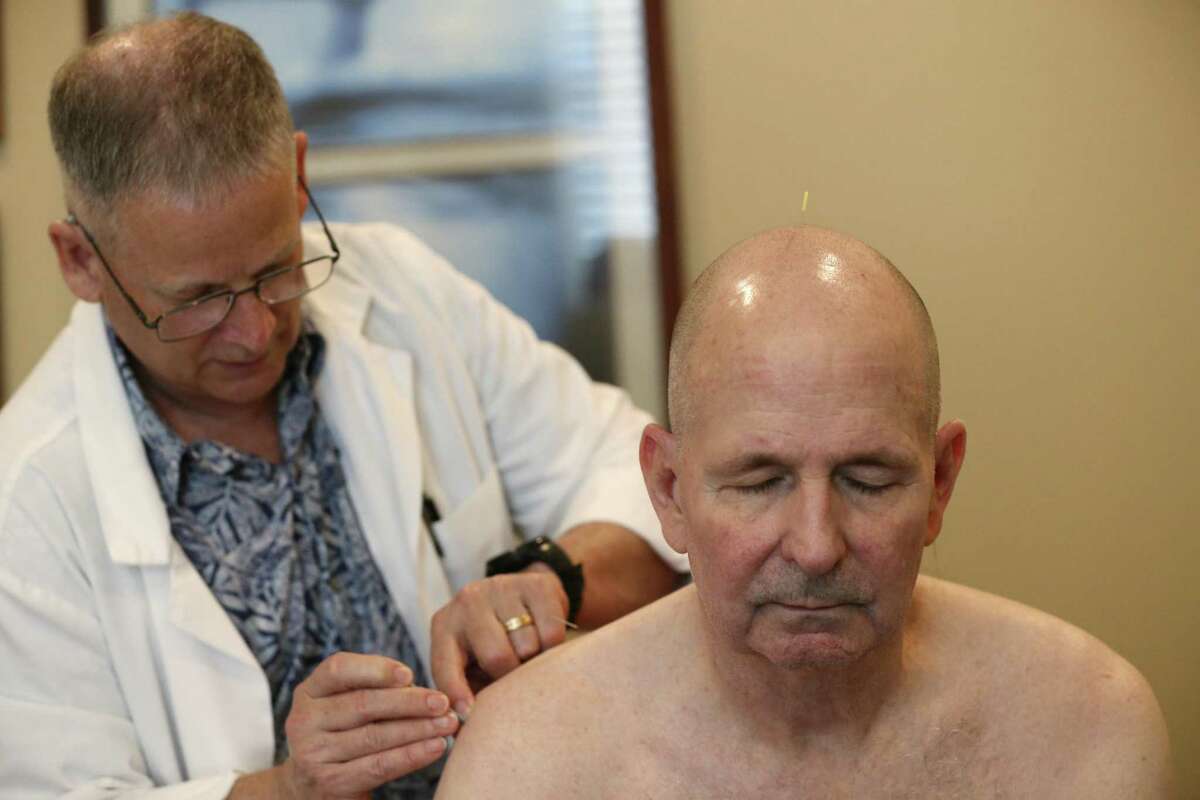Acupuncturist Michael Callaghan, left, works Winnett during a visit for pain relief.