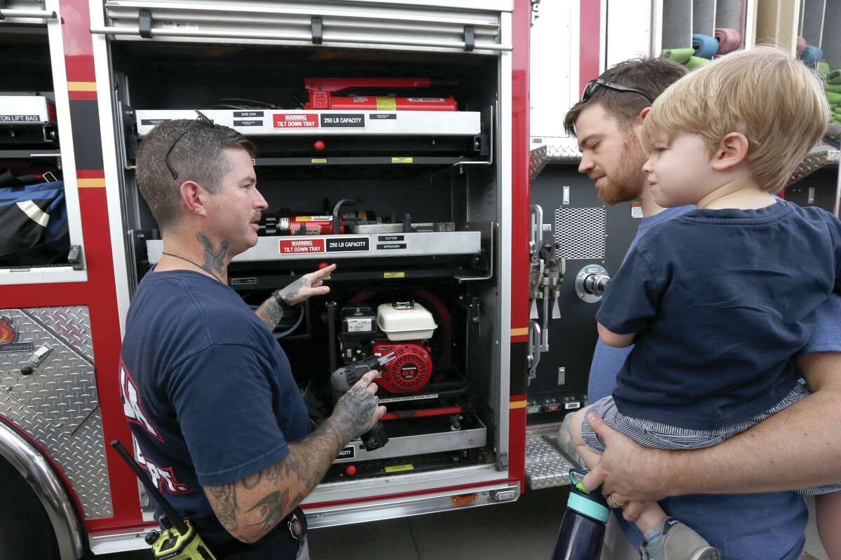 Magnolia firefighter Walter Sassard shows how various tools work on a fire engine to Magnolia resident Angus Fursdon-Welsh and his son Jude, 3, during a previous East 1488 Emergency Preparedness Fair.
