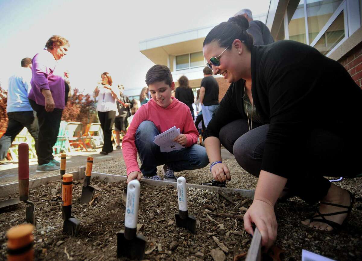 Student Dimitri Mysirlidis, 11, and teacher and garden committee member Courtney Dishian plant flower seeds in the new outdoor classroom at Perry Hill School in Shelton, Conn. on Monday, May 14, 2018.