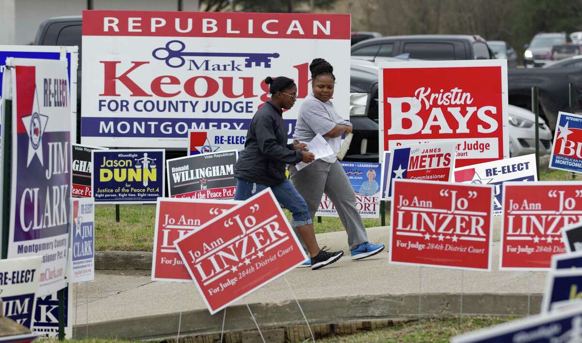 Voters walk by political signs that line the street to the East Montgomery County Courthouse on the first day of Early Voting, Tuesday, Feb. 20, 2018, in New Caney.