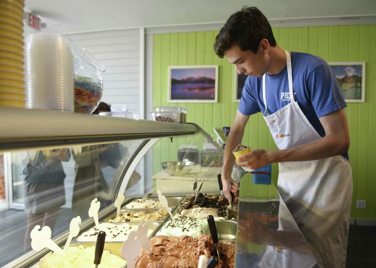 Employee Vittorio Marin scoops gelato behind the counter at Gelato & Cioccolato in the Cos Cob section of Greenwich, Conn. Tuesday, May 8, 2018. The new shop offers original Italian gelato from a family recipe born in northeastern Italy near Venice.