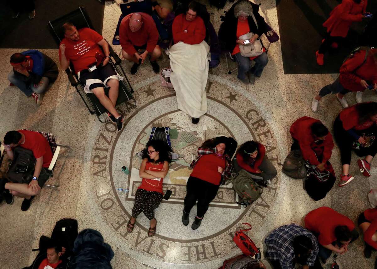 Some teachers sleep while waiting in the senate lobby during early morning hours as Arizona state legislatures continue to debate the State's budget Thursday, May 3, 2018, at the Capitol in Phoenix. The budget gives teachers big raises but falls short of their demands for better school funding. The teachers, in the sixth day of classroom walk outs, have agreed to return to the classroom once the budget has been approved by the legislature.