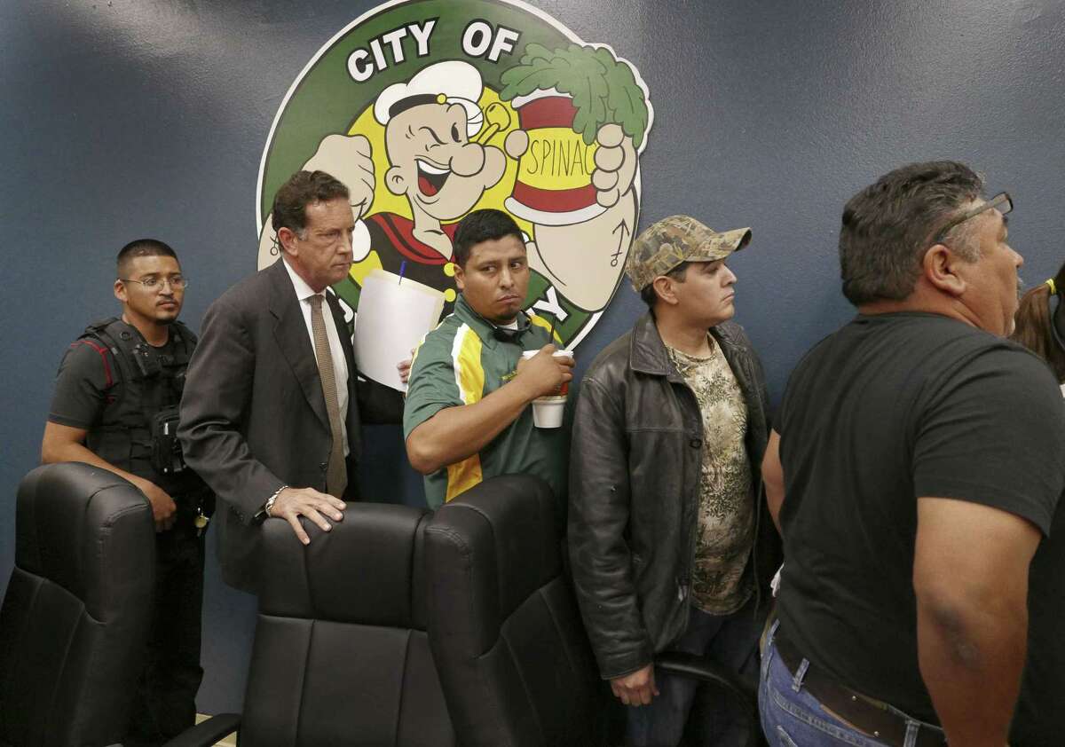 A police officer (left) escorts Crystal City attorney James Jonas, Councilman Marco Rodriguez, Mayor Ricardo Lopez and Councilman Joel Barajas from a meeting at which many citizens expressed anger at the council's proposed tax hike and attorney Jonas' high salary in this 2015 photo.