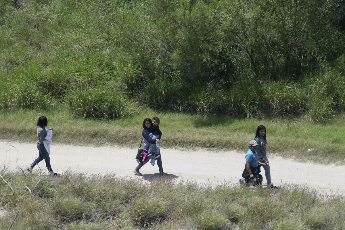 A group of immigrants, including children, walk along a road minutes after smugglers rafted them across the Rio Grande into the U.S. at a site called El Rincon, in Hidalgo County, Texas, May 11. Separating children from such parents now appears to be official policy.