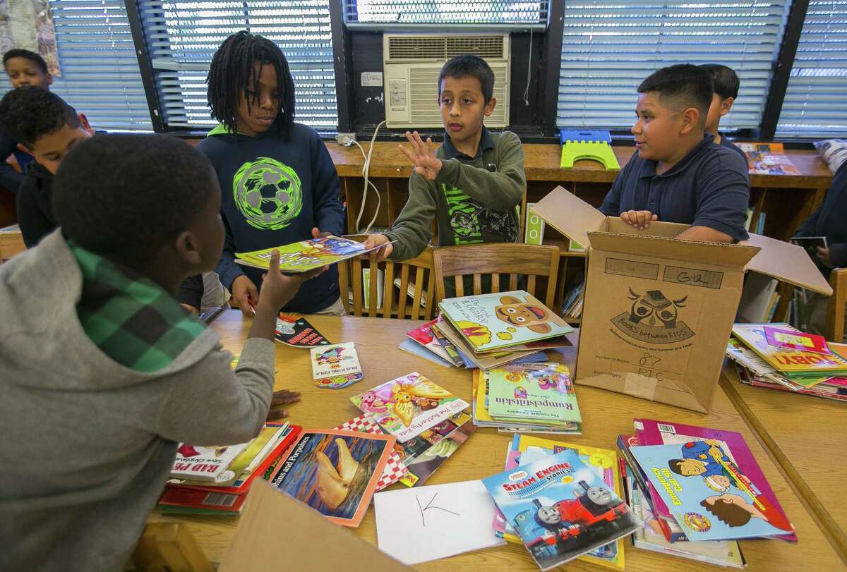 Oscar Mendez, 11, center, helps his fellow fifth graders sort library books into grade level groups inside the library at Kelso Elementary School, Thursday, May 17, 2018, in Houston. The library is cooled by a window unit air conditioner. Houston Independent School District administrators are making an initial recommendation that the district seek a $1.7 billion capital projects bond vote in May 2019 that would help replace schools like Kelso. ( Mark Mulligan / Houston Chronicle )
