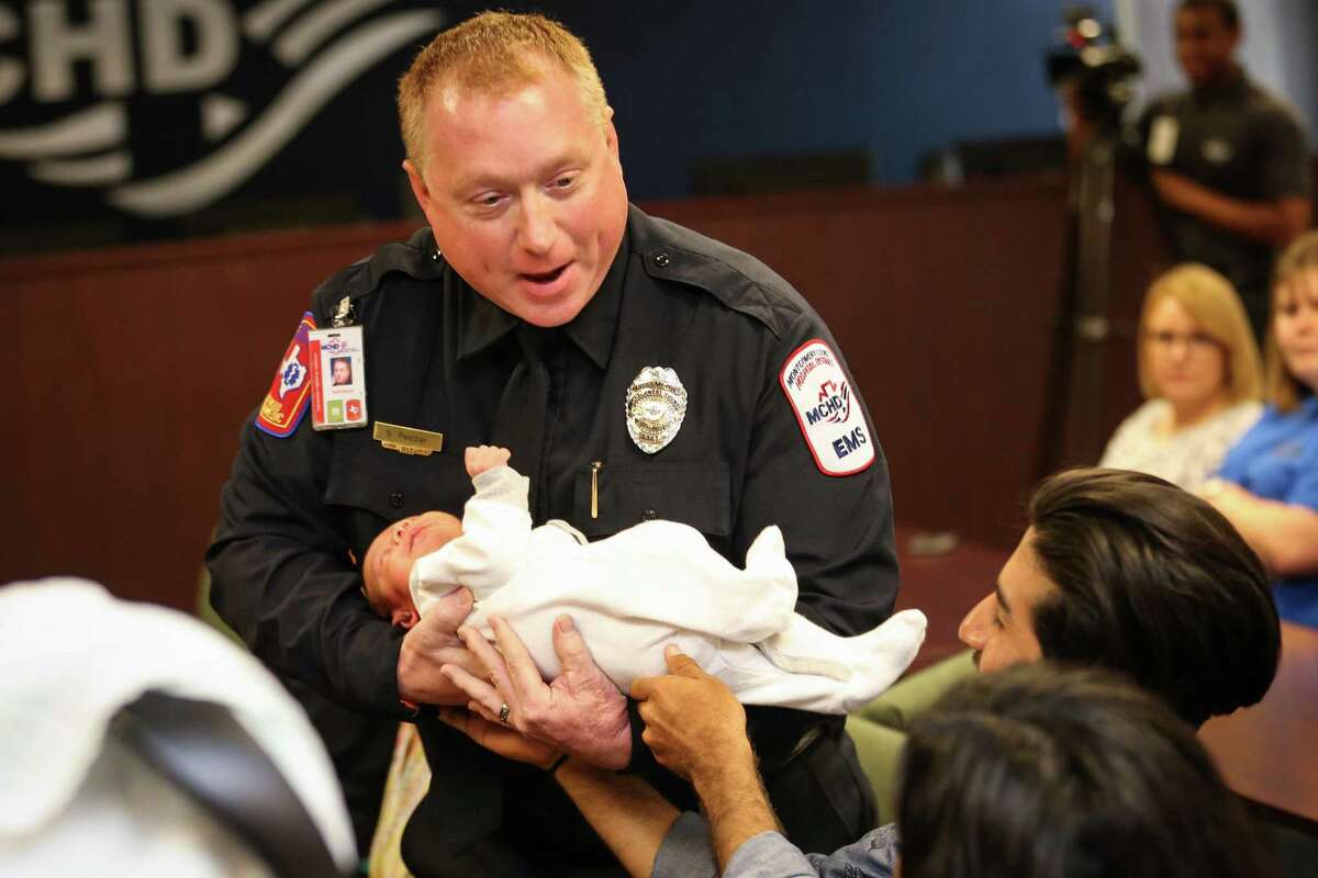 MCHD paramedic Scott Pelczar takes 2-week-old Aaron Santiago Perez, who was delivered in-home by Pelczar, during celebratory presentation on Friday, May 18, 2018, at the Montgomery County Hospital District Administrative Building.