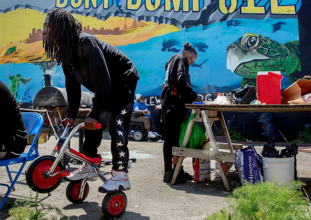 From left: Patrick Joseph on a tricycle as Shanay Rash makes a hot meal during a community cookout at the Bayview Roots Garden, Thursday, May 17, 2018, in San Francisco, Calif.