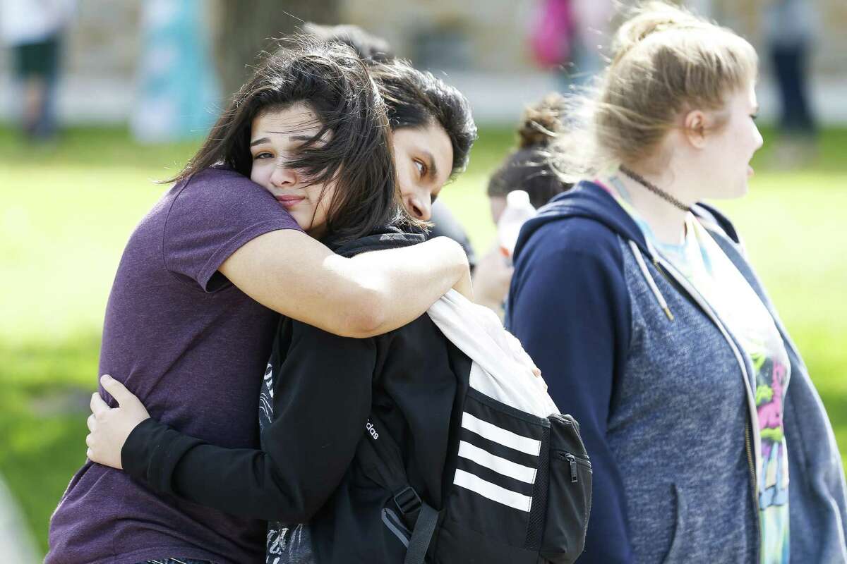 Santa Fe High School student Caitlyn Girouard, second from left, embraces a friend outside Alamo Gym where parents and students wait to be reunited after a mass shooting at Santa Fe High School Friday, May 18, 2018 in Santa Fe.