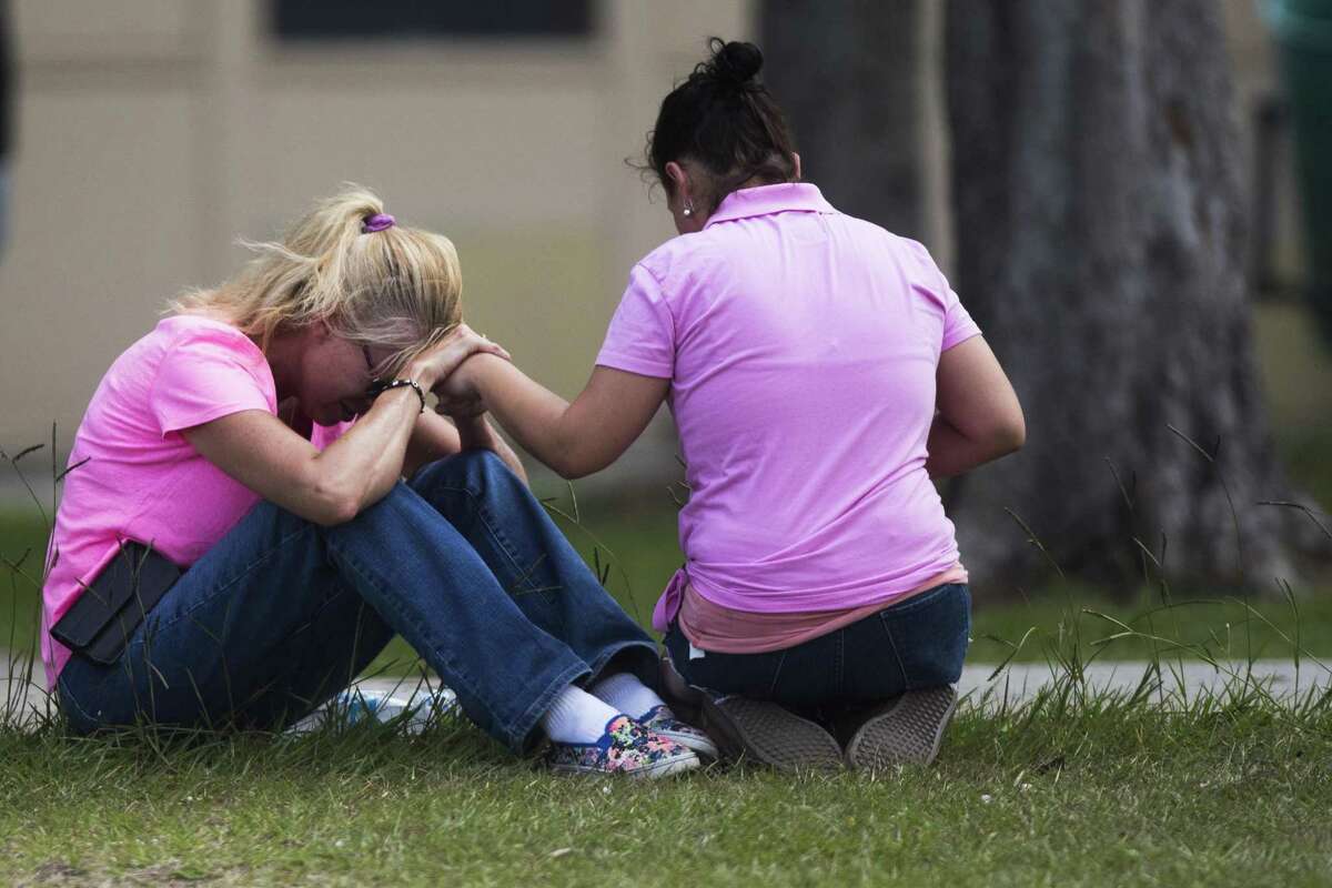 Two women pray outside the family reunification site following a shooting at Santa Fe High School on Friday, May 18, 2018, in Santa Fe, Texas.