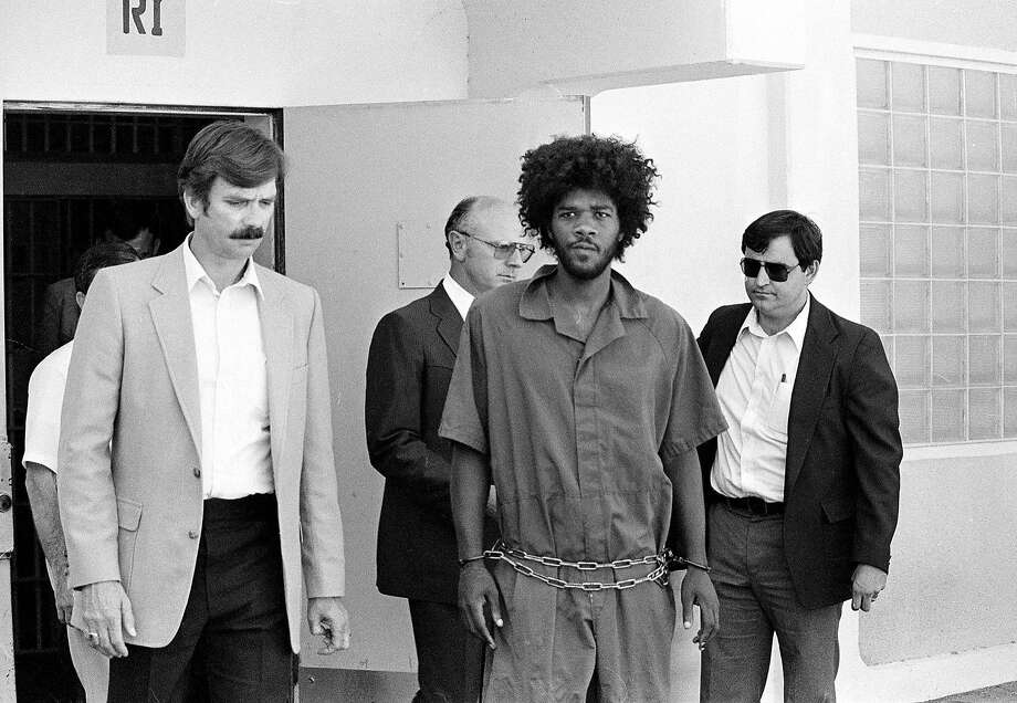 In this July 31, 1983, file photo, Kevin Cooper, center, a suspect in connection with the slashing death of four people in Chino, is escorted to a car for transport to San Bernadino from Santa Barbara, Calif., after he was arrested by police at Santa Cruz Island. U.S. Sen. Kamala Harris says California's governor should allow advanced DNA testing that advocates say could exonerate the death row inmate. Photo: / Associated Press