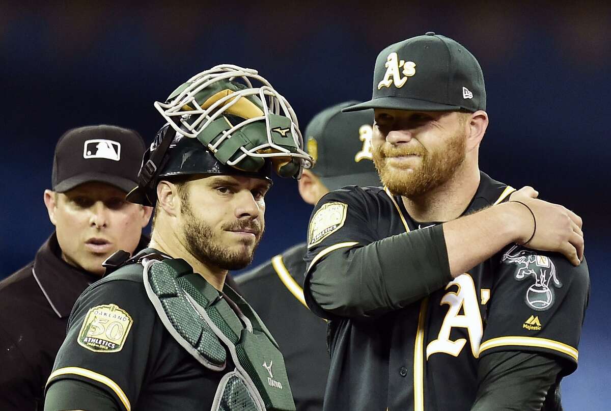 Oakland Athletics starting pitcher Brett Anderson, right, holds his arm as catcher Josh Phegley looks on in the second inning of a baseball game against the Toronto Blue Jays in Toronto, Friday, May 18, 2018. (Frank Gunn/The Canadian Press via AP)