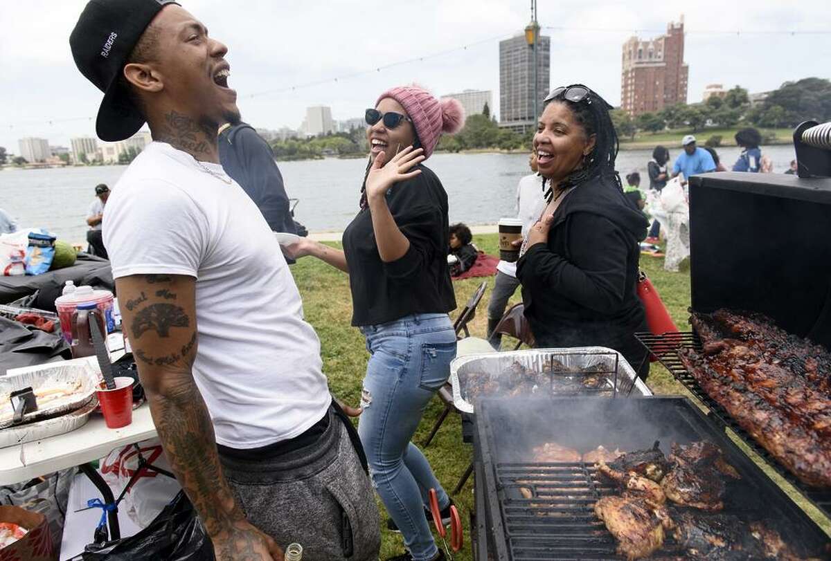 Michael Woods dances with his sister Clarice Brown (center) and their mother, Michelle Beasley, while tending to his grill.
