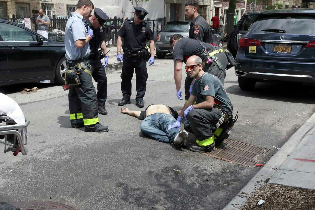 Emergency workers treat a person near the intersection of Broadway and Myrtle Avenue in Brooklyn, May 20, 2018. On Saturday, emergency workers treated 14 people believed to have been sickened by the synthetic drug known as K2, the police said. (Michelle V. Agins/The New York Times)