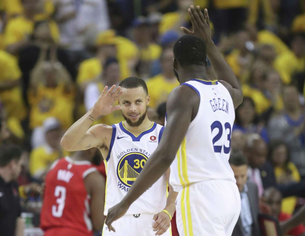 Golden State Warriors' Stephen Curry and Draymond Green high five in the third quarter during game 3 of the Western Conference Finals between the Golden State Warriors and the Houston Rockets at Oracle Arena on Sunday, May 20, 2018 in Oakland, Calif.