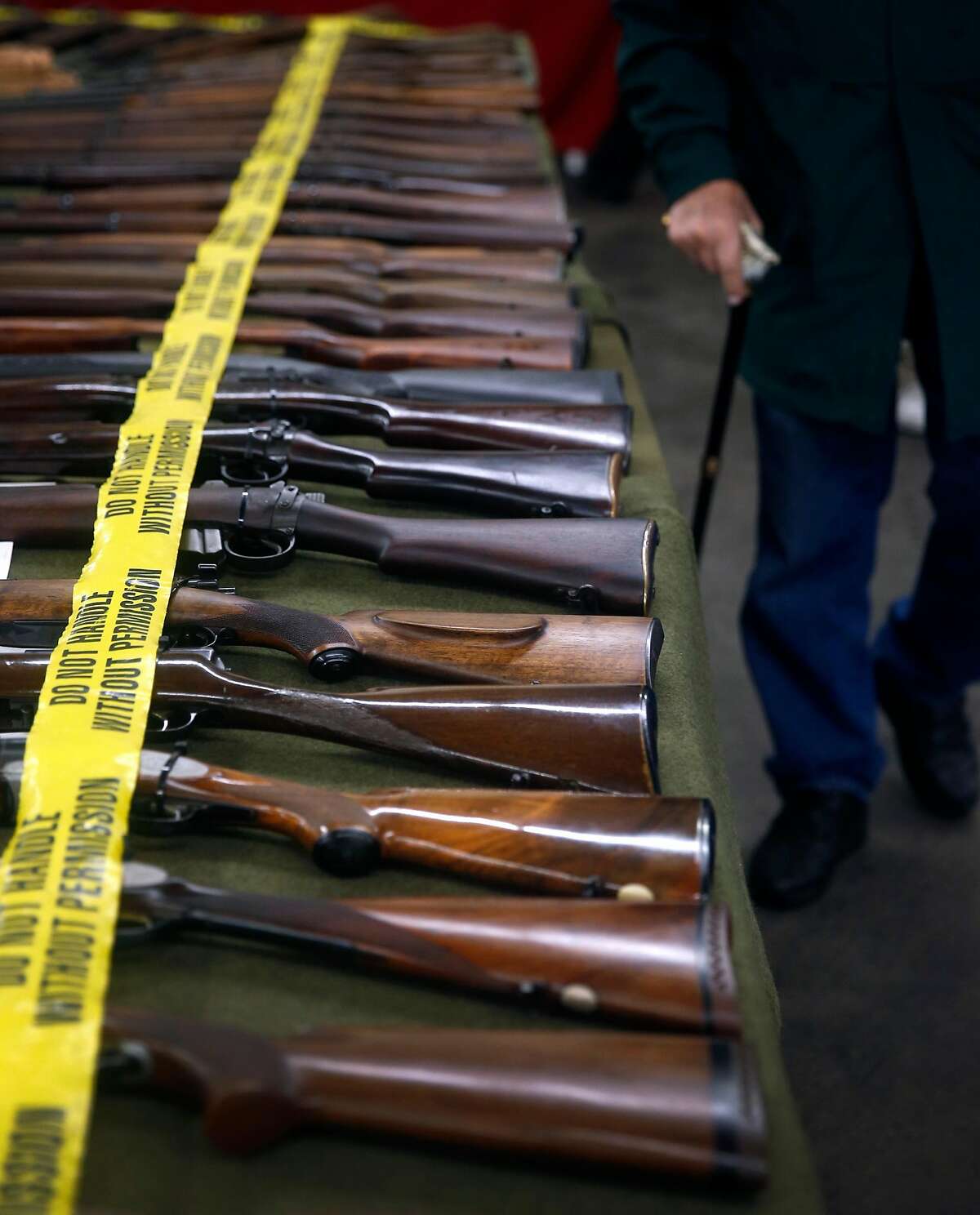 A man walks past an array of rifles at the Crossroads of the West gun show at the Cow Palace in Daly City, Calif. on Saturday, Jan. 9, 2016.