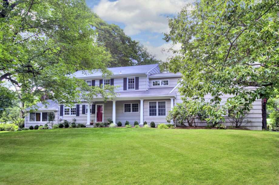 The gray colonial house at 15 Rockyfield Road has a covered front porch, 13 rooms, and 3,661 square feet of living space.
