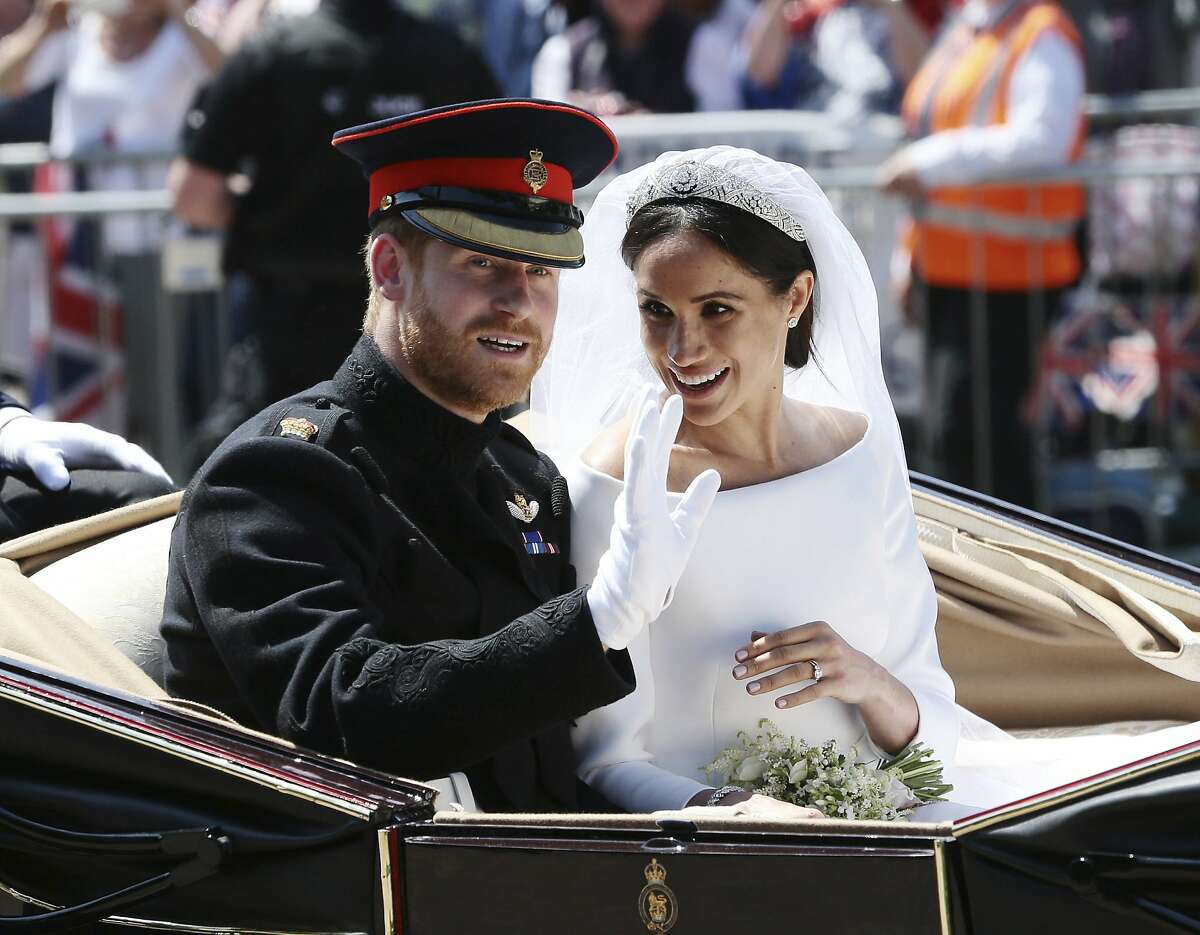 Britain's Prince Harry and Meghan Markle ride in an open-topped carriage after their wedding ceremony at St. George's Chapel in Windsor Castle in Windsor, near London, England, Saturday, May 19, 2018. (Aaron Chown/pool photo via AP)