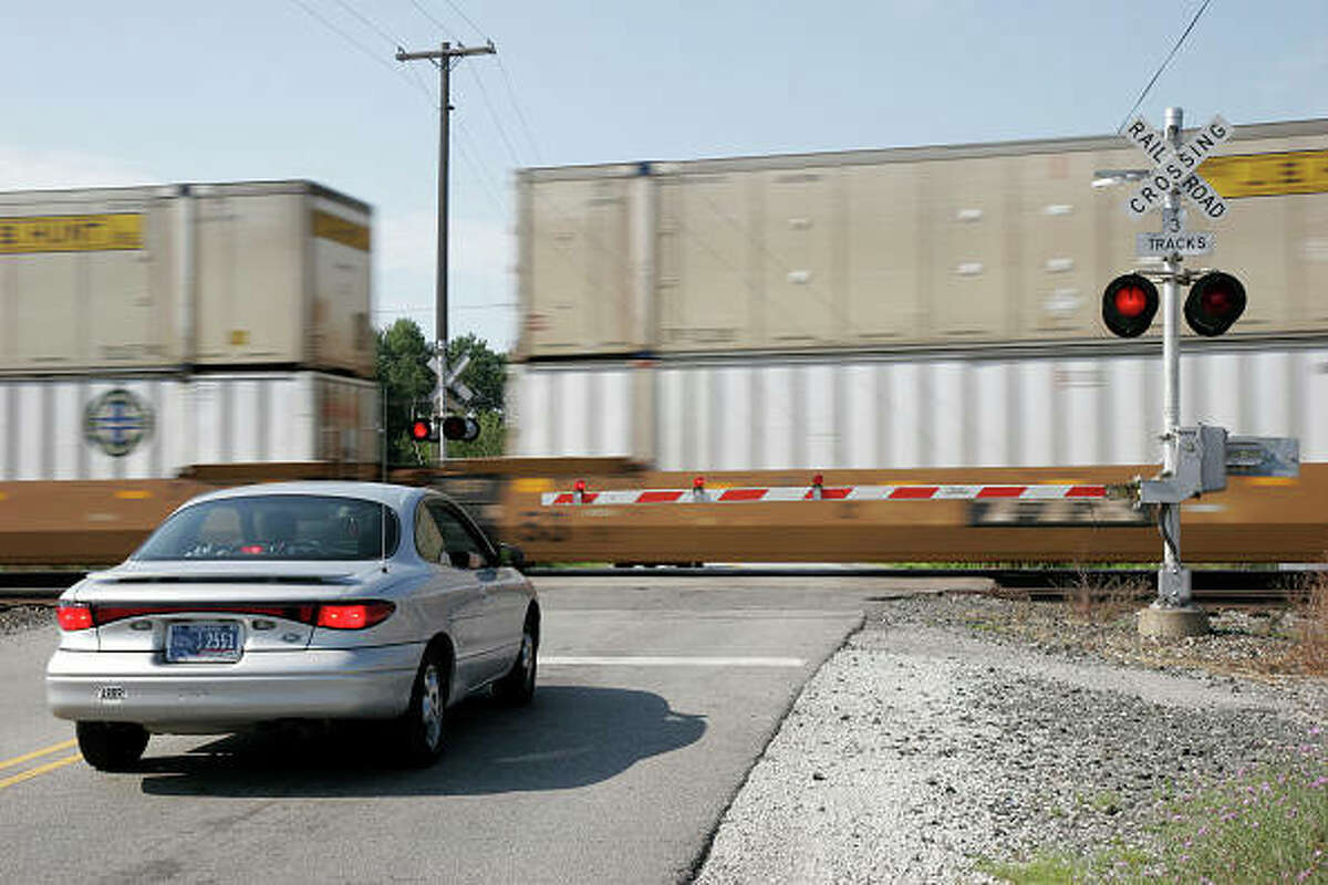 A car waits at a railroad crossing.