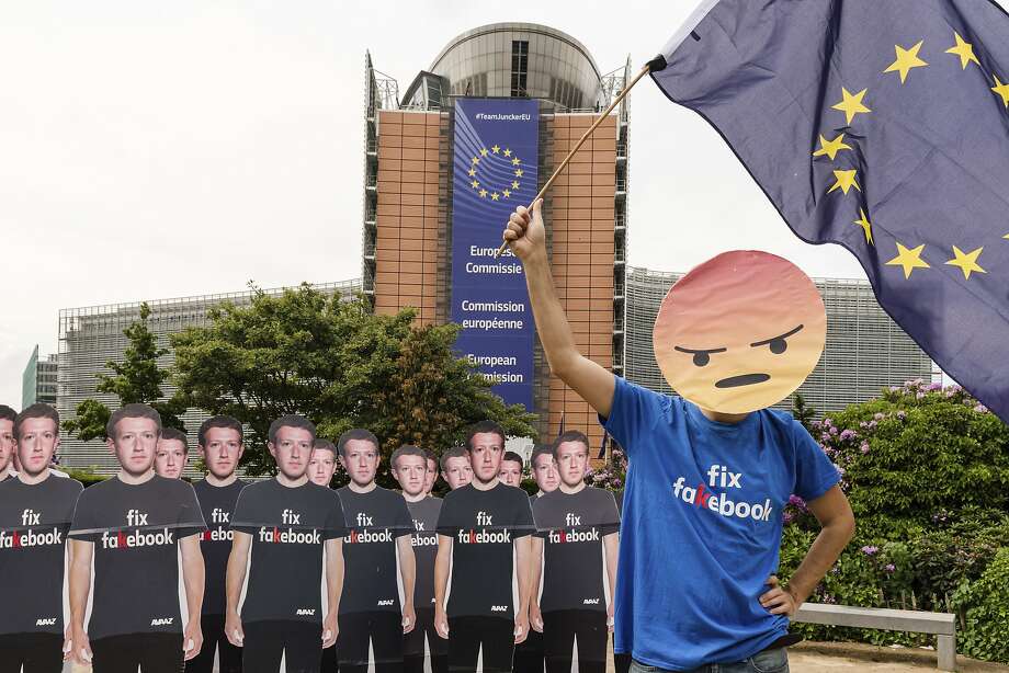 An activist protests in front of cardboard cutouts of Mark Zuckerberg outside the European Parliament building in Brussels, where the Facebook CEO answered questions about his firm. Photo: Geert Vanden Wijngaert / Associated Press
