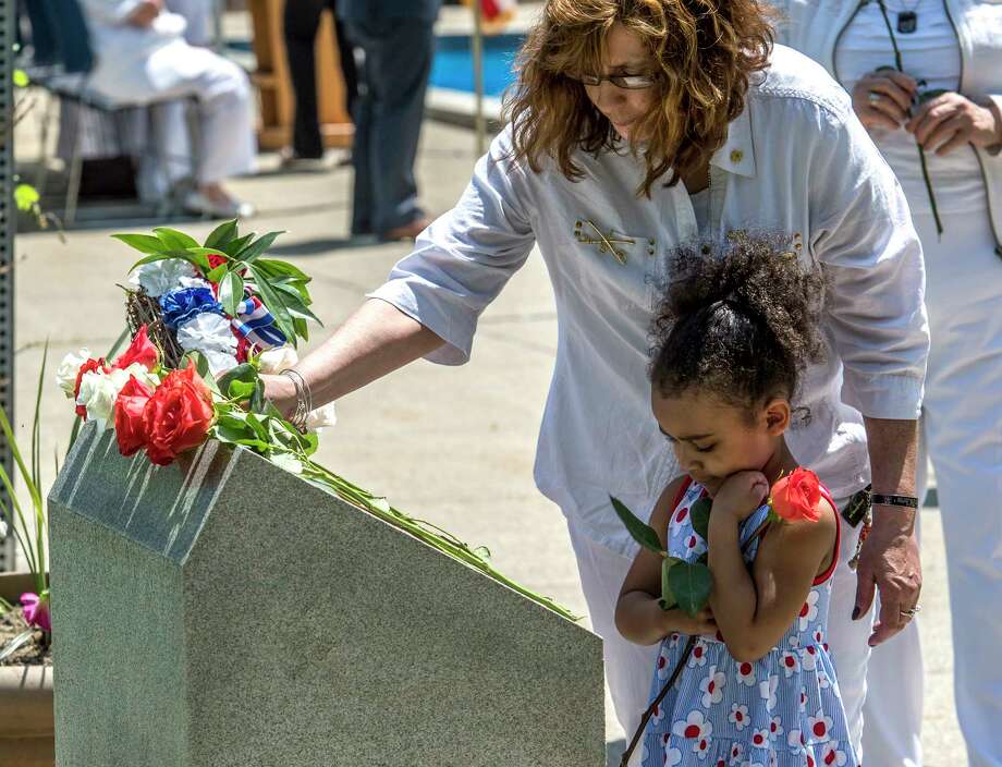 Kimberly Vandenburg of the Albany Chapter of the American Gold Star Mothers assists her granddaughter Zaniya Donaldson 5 of Schenectady in placing a carnation on the memorial stone for fallen service members at the the 25th annual Memorial Day Ceremony at the Department of Labor on the Harriman Campus Wednesday May 23, 2018 in Albany, N.Y.  (Skip Dickstein/Times Union) Photo: SKIP DICKSTEIN, Albany Times Union / 20043882A