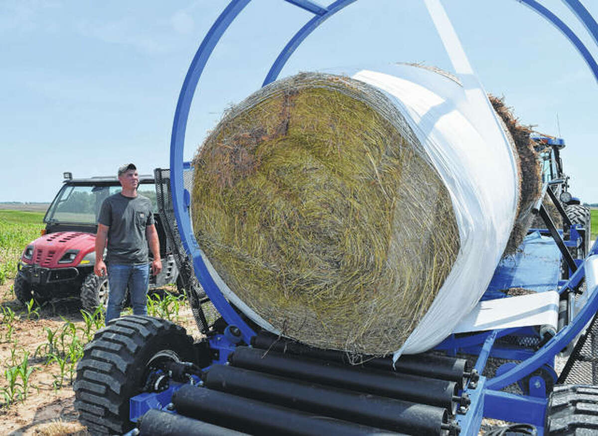 Austin Tomhave of rural Jacksonville watches a machine wrap hay bales in plastic on his family farm. The wrapping helps maintain quality hay.