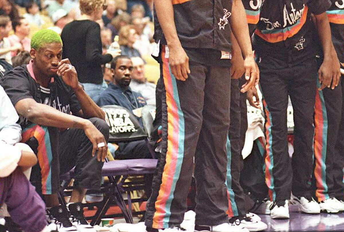 INGLEWOOD, UNITED STATES: Dennis Rodman (L), the leading rebounder for the San Antonio Spurs, sits on the bench during a timeout at their 14 May playoff game with the Los Angeles Lakers in Inglewood, California. Rodman was benched for this game, by coach Bob Hill, because of his behavior in the last game. The Spurs won, 80-71, to take a 3-1 lead in the western conference semi-final series. AFP PHOTO (Photo credit should read Vince Bucci/AFP/Getty Images)