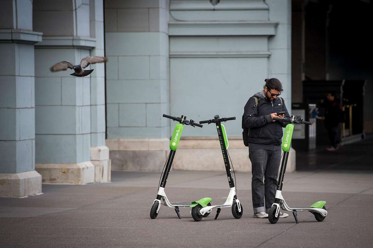 A rider checks the status of a LimeBike scooter in San Francisco, California, U.S., on Tuesday, May 15, 2018. Neutron Holdings Inc. LimeBike is one of a handful of companies that�have spent the last few months sprinkling hundreds of bikes and�electric�scooters around American�cities. They allow�people to unlock the�vehicles with smartphone apps and ride them for as little as $1, leaving them sitting on the sidewalk when they've reached their destination. Photographer: David Paul Morris/Bloomberg