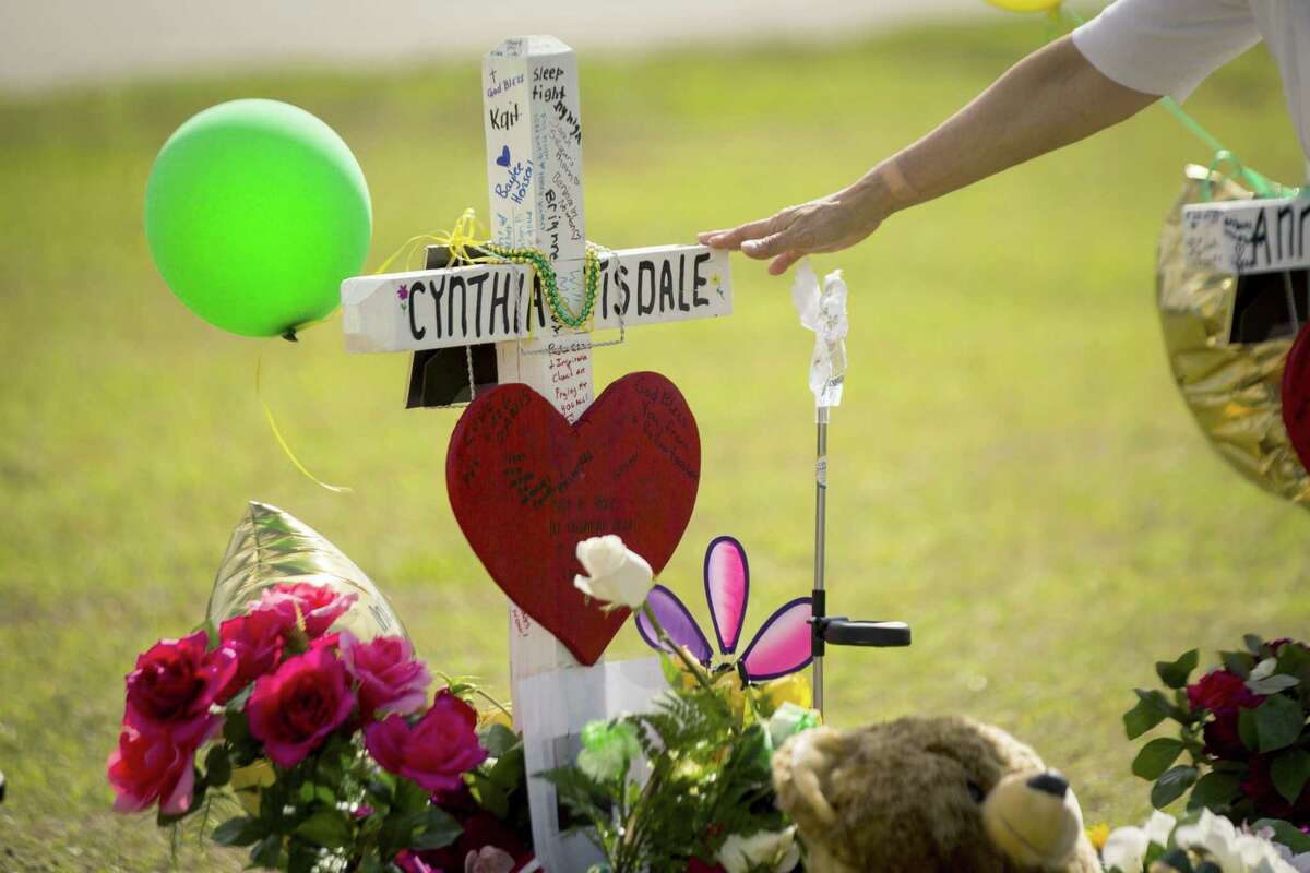 A woman gestures toward a cross honoring Santa Fe High School substitute teacher Cynthia Tisdale Tuesday, who was killed during a shooting at the school on Friday, in Santa Fe, Texas.